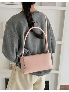 Stylish pink baguette shoulder bag for women, trendy underarm purse with cute chain charm.