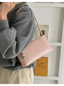 Minimalist pink shoulder bag for women, stylish underarm baguette bag with metal charm detail.