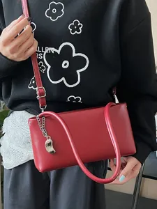 Chic red baguette shoulder bag for women, trendy underarm purse with chain charm.