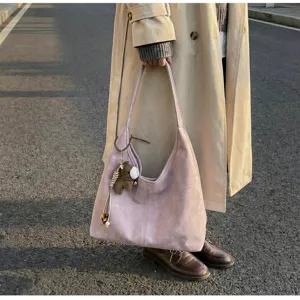 Gros plan sur le sac porté épaule élégant en suédine, montrant sa grande capacité et breloque.