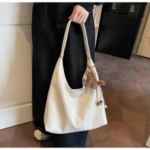 Vue détaillée du sac porté épaule blanc souple avec charmant pendentif en peluche.