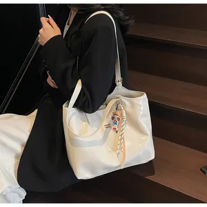 Close-up detail shot of a stylish white patent leather tote bag worn by model on stairs.