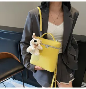 Detail view of a stylish yellow textured handbag with a cute bear plush pendant.