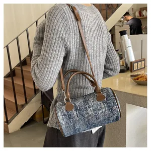 Stylish denim textured barrel shoulder bag with brown leather handles and strap for women.