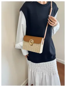 Close-up view of a stylish straw woven crossbody bag with brown leather flap and gold ring.