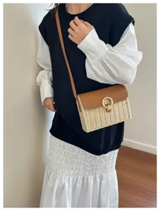 Detail view of vintage straw crossbody bag with brown leather flap and golden ring lock.