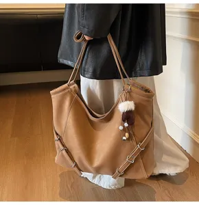 Detailed shot of a stylish brown slouchy tote shoulder bag with side buckle straps and charm.