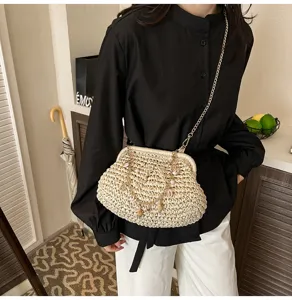 Stylish straw woven shoulder bag detail, featuring chain strap and shell pearl charms.