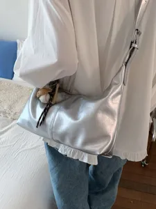 Silver hobo shoulder bag for women, stylish casual crossbody dumpling bag with charm.