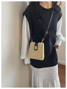 Detail view of the retro straw woven handbag with black beaded handle and stylish metal lock.