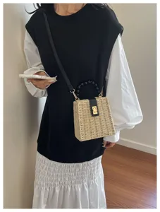 Detailed shot of retro straw box bag featuring black bead handle and chic gold turn-lock.