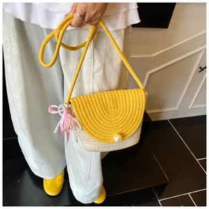 Detail of handmade woven mini crossbody bag with yellow flap, pearl clasp and ribbon.