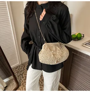 Detailed view of women's woven straw crossbody bag with chain strap and pearl decor.