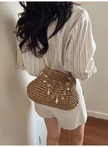 Woven straw shoulder bag featuring a metal chain strap and delicate seashell pearl charms.