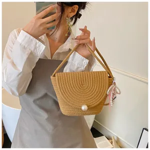 Handmade woven straw crossbody bag with elegant pearl closure and cute pendant charm.