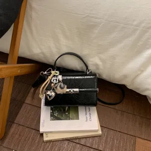 Μίνι τσάντα χειρός και χιαστί από μαύρο λουστρίνι με μεταλλική κλειδαριά και γούρια.