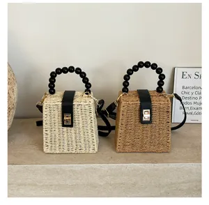 Detailed shot of retro woven straw handbags featuring elegant black bead handles and gold lock.
