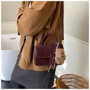 Retro frosted leather crossbody bag with cute plush bear pendant and stylish handle design.