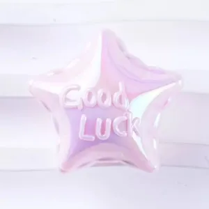 Close-up of pink iridescent acrylic star bead with embossed good luck text for DIY jewelry.