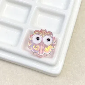 Close-up detail of a cute iridescent pink cookie shaped DIY bead with large funny eyes.