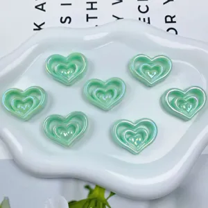 Vista detallada de cuentas de corazón de acrílico verde, ideales para joyería de bricolaje.
