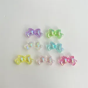 Primer plano de accesorios lazo de acrílico colorido, dijes de joyería DIY irisados, dulce diseño.