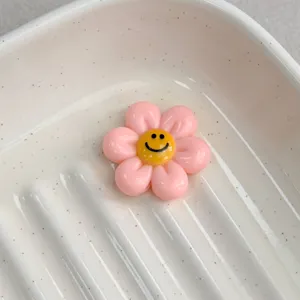 Cute pink resin flower charm with a smiling face, perfect for DIY jewelry and hair accessories.