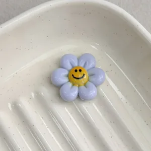 Resin purple smiley flower charm close-up, perfect DIY accessory for bracelets and crafts.