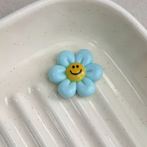 Blue resin smiley flower cabochon detail shot for DIY jewelry making and cute craft accessories.