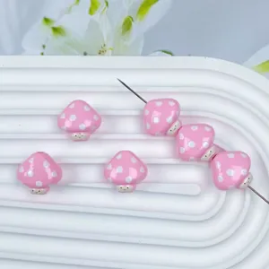 Dettaglio di perline di funghi a pois rosa carini, perfette per gioielli fatti a mano fai da te.