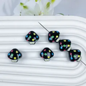 Primo piano dettagliato di perline a fungo nere con pois colorati per gioielli fai da te.