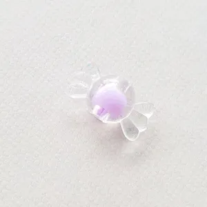 Primer plano de cuenta acrílica transparente con forma de caramelo y núcleo morado DIY.