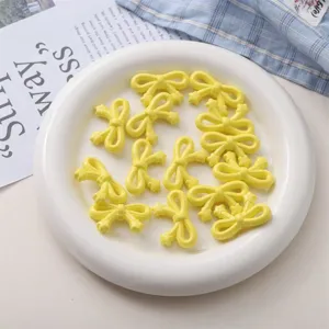 Détail de perles nœud papillon étoile acrylique jaune, parfait pour bijoux DIY et accessoires.