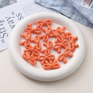 Gros plan détaillé de perles nœud en acrylique orange sur assiette blanche pour bijoux faits main.