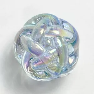 Close-up detail of iridescent acrylic woven knot bead, colorful shiny DIY jewelry accessory.