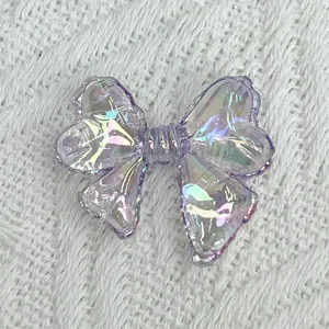Detailed close-up of a transparent iridescent purple bow acrylic charm for DIY jewelry crafting.