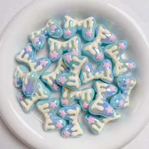 Acrylic macaron bow beads with dripping cream and pink stars, perfect for DIY phone charms and crafts.