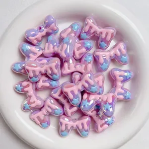 Acrylic macaron bow beads closeup, sweet pink drip design with blue stars for DIY craft making.