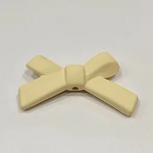 Dettaglio macro di un accessorio DIY con fiocco giallo chiaro, ideale per cover e mollette.