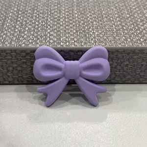 Dettaglio dell'accessorio molletta per capelli con fiocco in resina viola, fai da te.