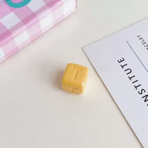 Primo piano perla cubo acrilico giallo con lettera, ideale per accessori braccialetto fai da te.