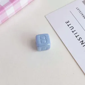 Primo piano dettagliato di perla a cubo in acrilico azzurro con lettera B in rilievo.
