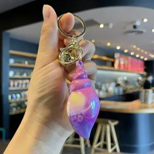 Detailed shot of the colorful acrylic conch shell keychain pendant with gold tone hardware.