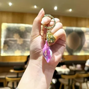 Close-up of cute pink iridescent conch keychain with gold bell and ring, detail shot.