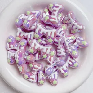 Close-up detail of iridescent acrylic macaron bow beads with white drip and green star decor.
