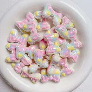 Close-up detail of pastel acrylic bow beads with glossy drip glaze design for DIY crafts.