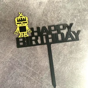 Close-up detailopname van de zwarte acryl Happy Birthday taarttopper met gele robot figuur.