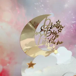 Gold acrylic crescent moon cloud cake topper with Dream Big Little One text for party decor.