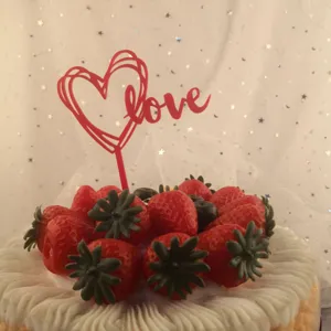 Red acrylic love heart cake topper for Valentine's Day party and romantic celebration decor.