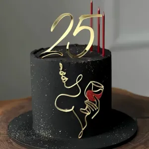 Close-up of minimalist black cake with gold acrylic 25 topper and artistic face line decoration.